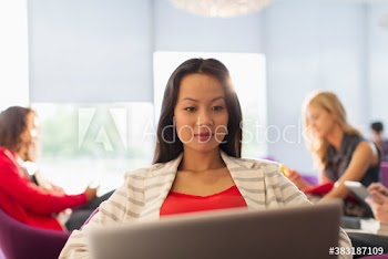 Female college student using laptop in student lounge