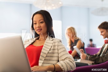 Female college student using laptop in student lounge