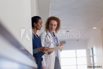 Female doctor and nurse consulting in hospital corridor