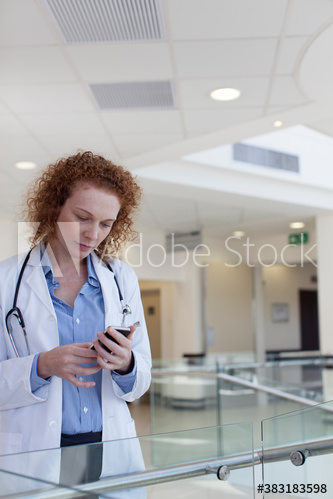 Female doctor using smart phone in hospital corridor