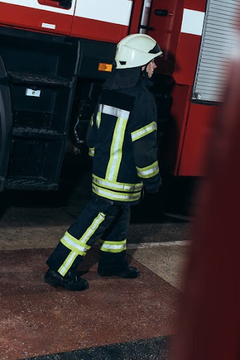 Female firefighter in uniform and helmet walking at fire station