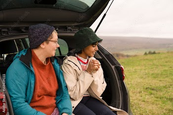 Female friends sitting in car trunk after hiking
