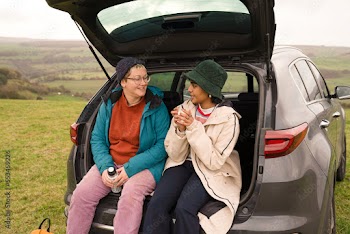 Female friends sitting in car trunk after hiking