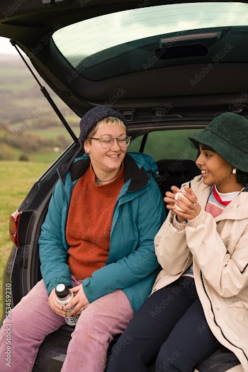 Female friends sitting in car trunk after hiking
