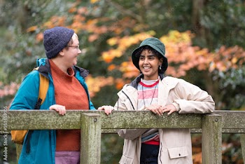 Female friends standing on bridge in forest