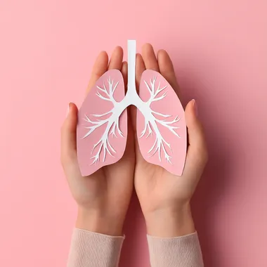 Female Hands Holding Paper Lungs on Pink Background - Lung Cancer Awareness