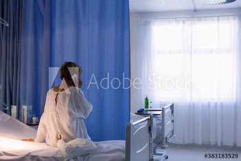 Female patient using smart phone in hospital bed