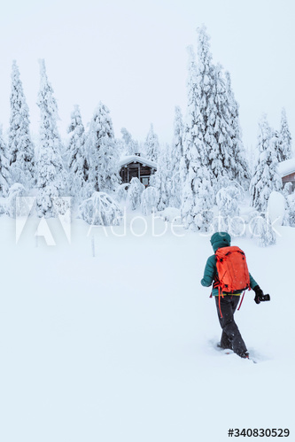 Female photographer walking to a cabin in the snowy woods