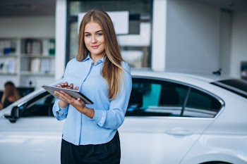 Female salesperson at a car showroom by the car Free Photo