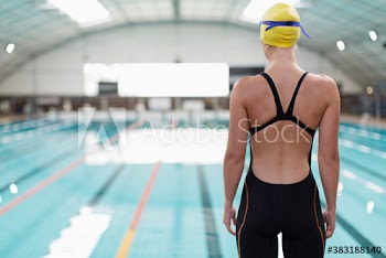 Female swimmer standing at indoor swimming pool