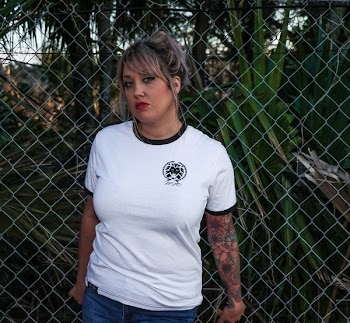 Female Wearing Black and White Crew-neck T-shirt and Blue Denim Bottoms Leaning on Chicken Wire