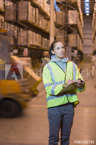 Female worker with clipboard checking inventory in distribution warehouse
