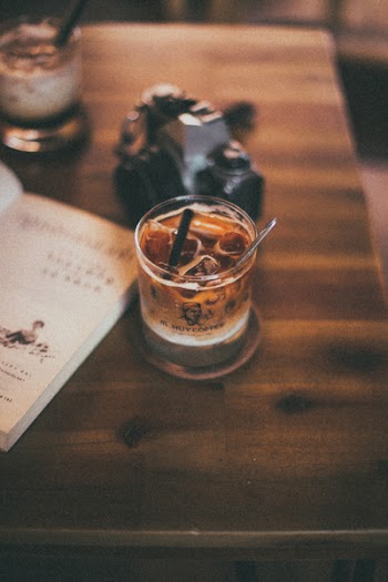 Filled Pint Glass Beside Camera and Book on Table