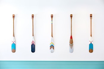 five assorted-color oars on white wall