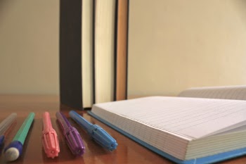 Five Assorted-color Pens Beside Blue Lined Paper
