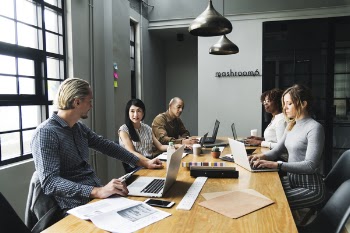 Five Person Sitting Front of Conference Table With Laptop Computers