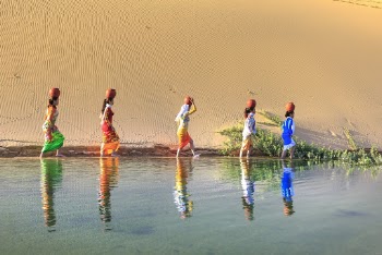 Five Women Walking Near Water With Pot on Head