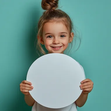 Five-Year-Old Girl with Messy Bun Smiling Behind White Paper Circle Five-Year-Old Girl with Messy Bun Smiling Behind White Paper Circle