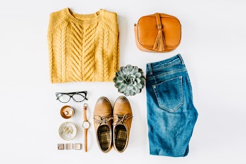 flat lay feminini clothes and accessories collage with brown cardigan, jeans, glasses, watch, earrings, purse, boots and succulent on white background.