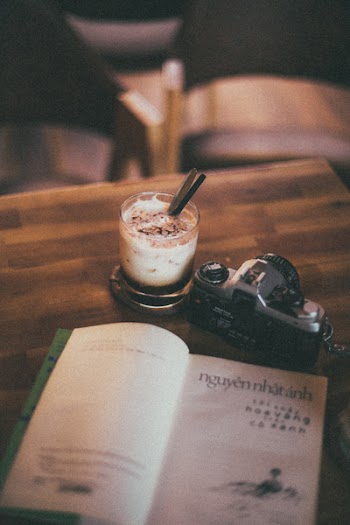 Flat Lay Photography of Camera, Book, and Milk on Table