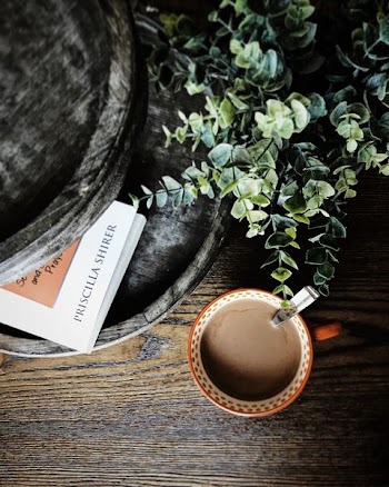 flat lay photography of coffee cup beside plant and book