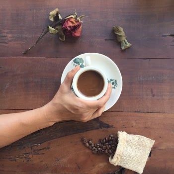 Flat Lay Photography of Person Holding White Ceramic Cup With Liquid Inside