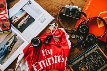 flat lay photography of soccer jersey, books, headphones, and camera