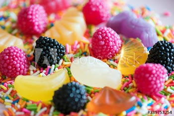 Flatlay of assorted jelly fruits and sprinkles textured background