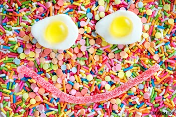 Flatlay of jelly fried eggs forming a smiley face and sprinkles textured background