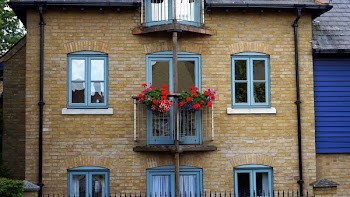 Flowers Hanged on Balcony Railing Near Windows