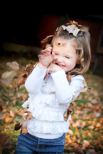 Focus Photo of Girl in White Long Sleeve Shirt With Brown Leaf on Her Head