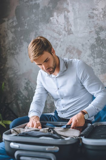 Focused businessman packing luggage in suitcase in bedroom at home