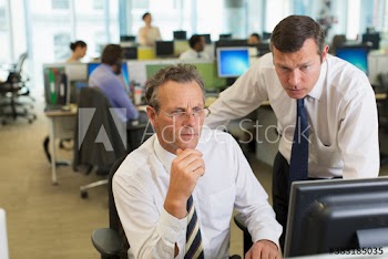 Focused businessmen using computer in open plan office
