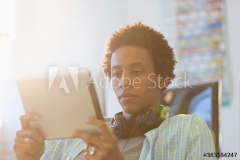 Focused young creative businessman with headphones using digital tablet