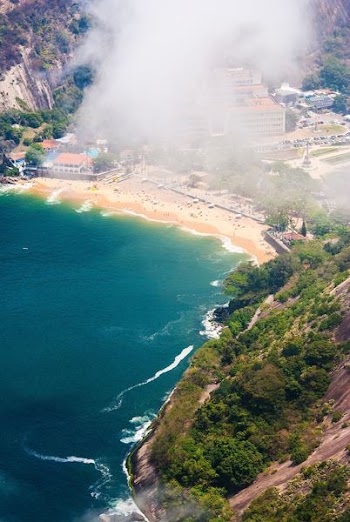 fog covering mountain near body of water