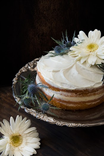Fondant Cake Whipped With White Icing and Topped With White Petaled Flower on Grey Stainless Steel Plate