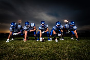 Football Players in Blue Jersey Lined Under Grey White Cloudy Sky during Sunset