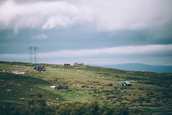 four houses on green grass field under cloudy sky