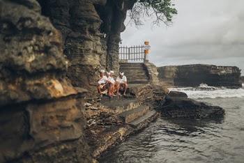 Four Men Sitting on Stairs Front of Body of Water