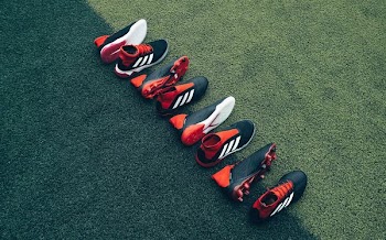 four pairs of black-and-orange shoes laid on green grass