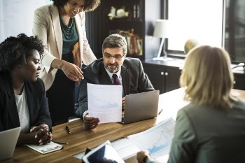 Four People Discussing Near Table Inside Room