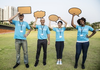 Four People Standing on Field Holding Conversation Bubbles