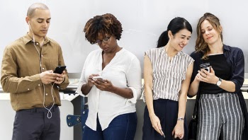 Four People Standing using Their Phones