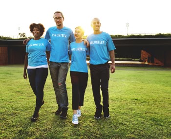 Four People Walking on Green Grass Field