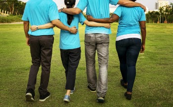 Four People Walking While Holding Each Others Arms