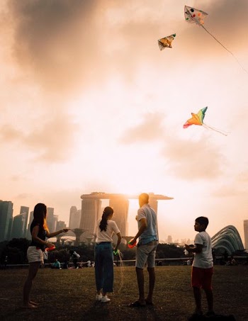 four person playing kite on grass field