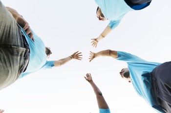 Four Person Raising There Hands Above the Sky