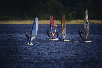 Four Person Riding Wind Sailboard on Body of Water