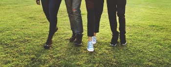 Four Person Standing on Green Grass Field