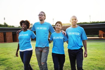 Four Person Wearing Blue Shirts With Volunteer Print Outdoors